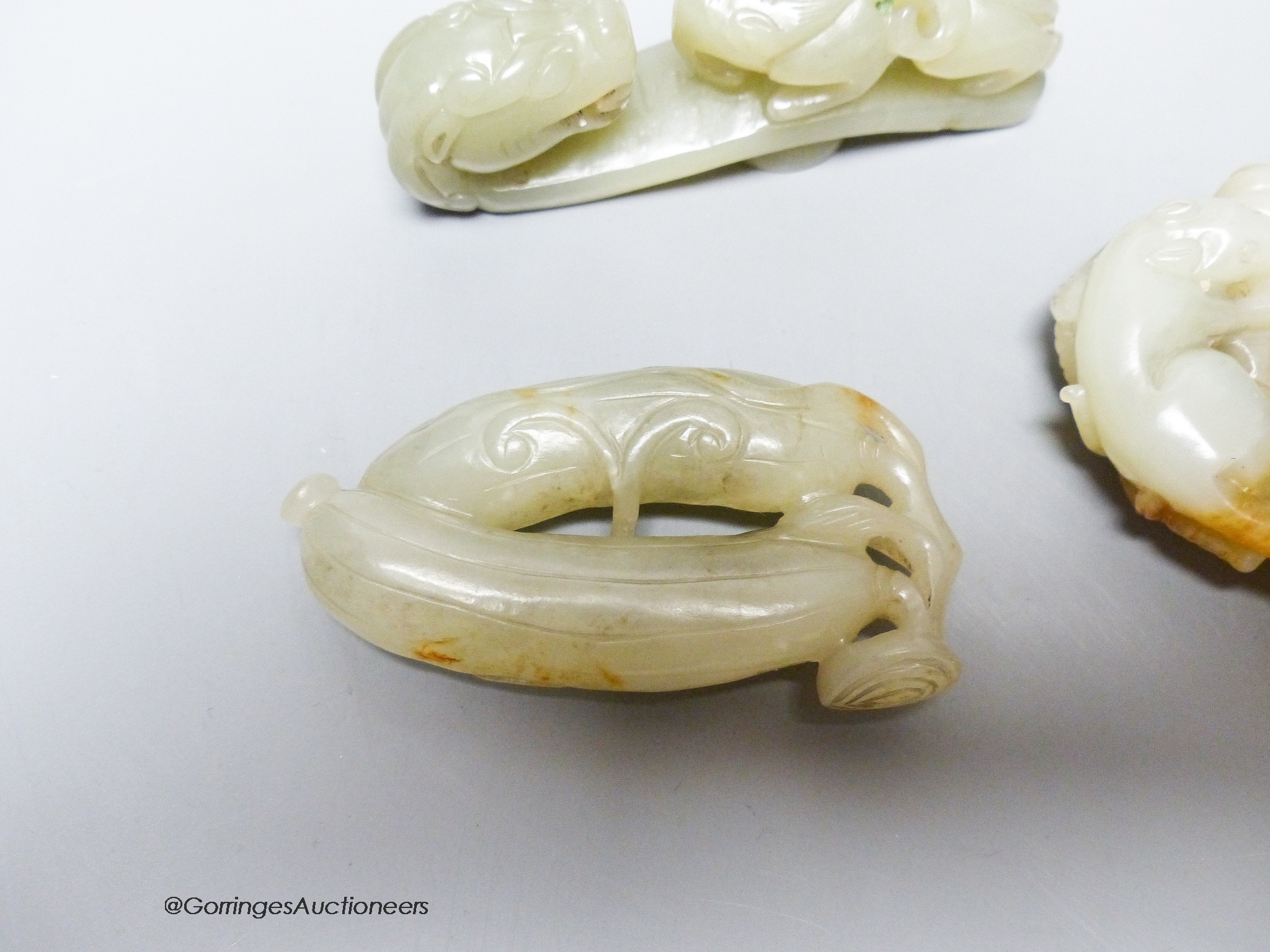 Three Chinese celadon jade carvings, a 'squirrel' brushwasher, 'dragon' belt hook and a carving of bitter melons, 7.5 - 11cm